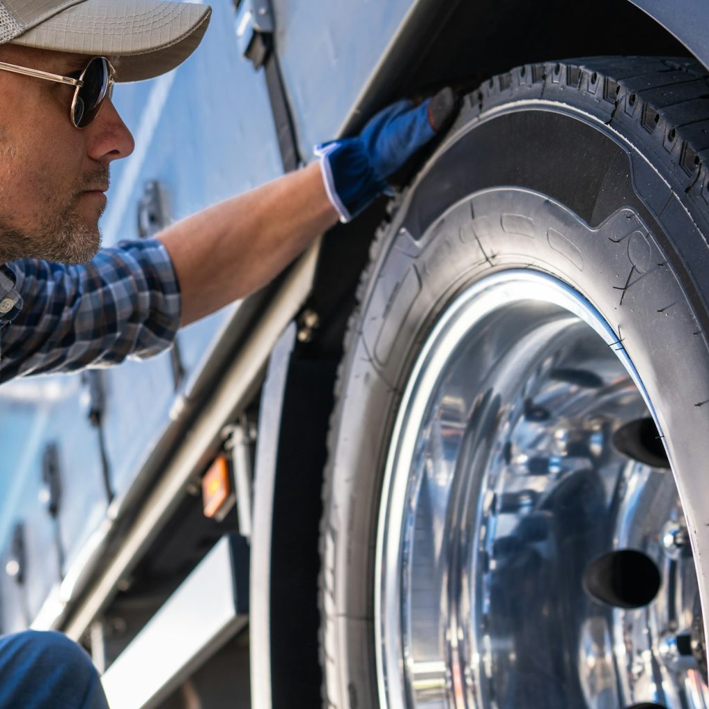 Trucker Examining a Tire on a Truck.