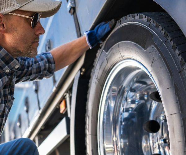 Trucker Examining a Tire on a Truck.