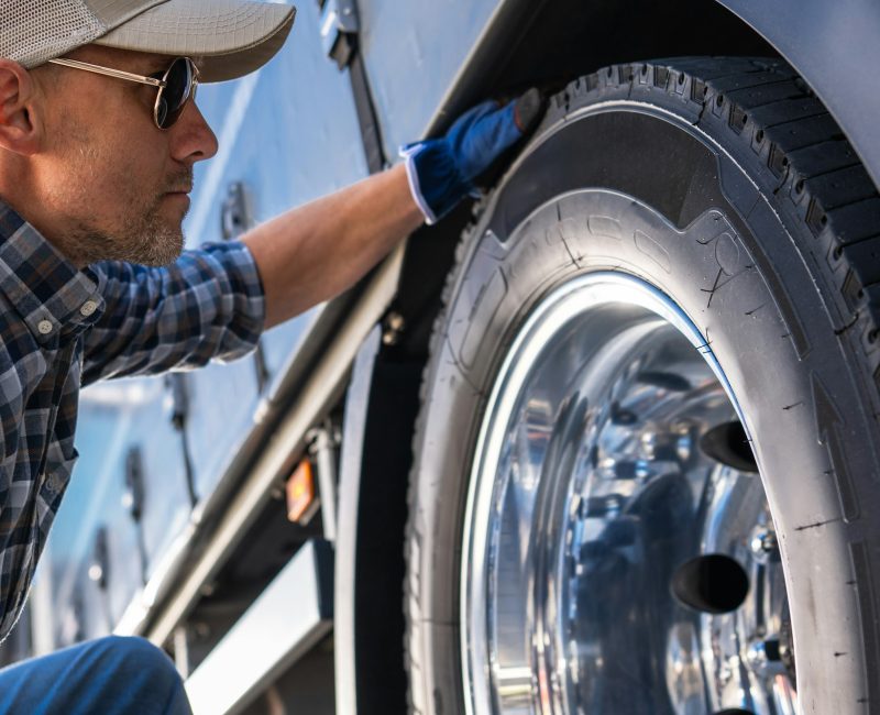 Trucker Examining a Tire on a Truck.